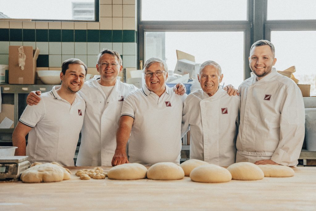 Die Generationen auf einem Bild. Frank und Josef jun. Lehrbach mit drei Generationen der Zehetmaier Familie. Zusammen stehen sie in der Backstube neben frischem Teig und Mehl.
