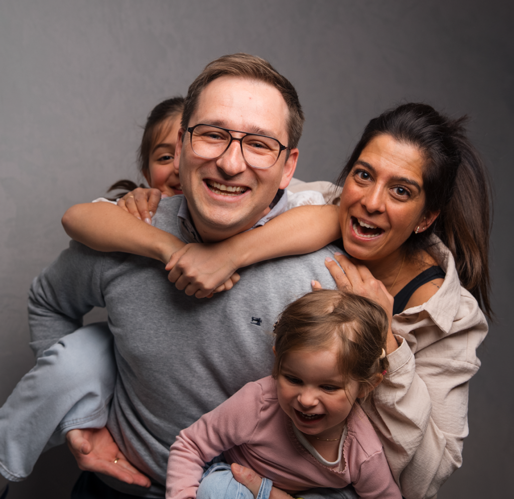 Familienfoto der Familie Lehrbach 2025. Carina und Frank mit ihren beiden Kindern lachen und albern vor der Kamera.