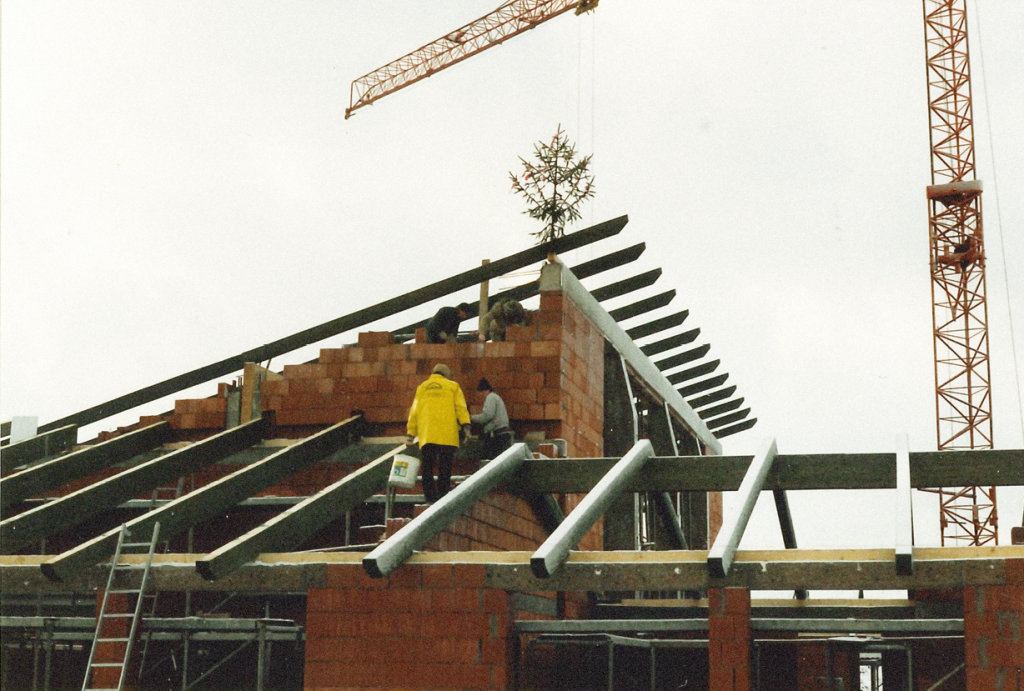 Foto von der Baustelle 1988. Richtfest. Personen maurern an dem neuen Gebäude.