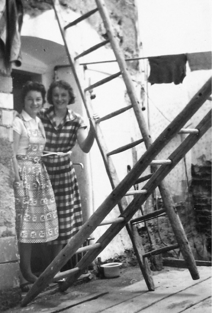 Bild der Baustelle des Umbaus 1961-1964. Zwei Frauen stehen hinter zwei Leitern und lächeln in die Kamera.