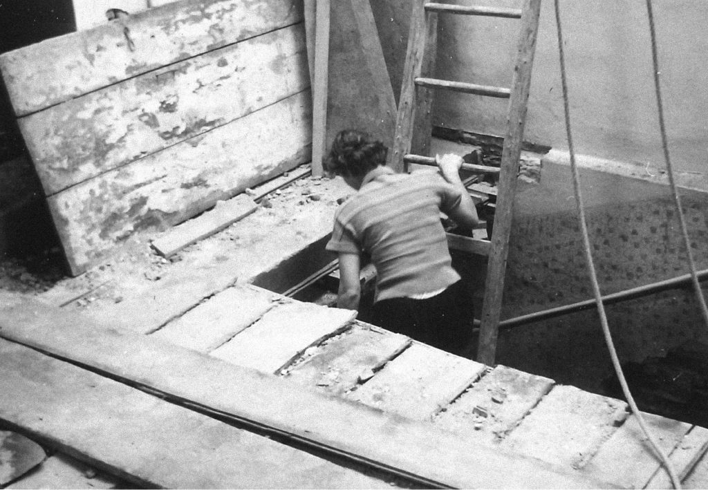 Bild der Baustelle des Umbaus 1961-1964. Eine Frau steigt eine Leiter in ein darunterliegendes Stockwerk hinunter.
